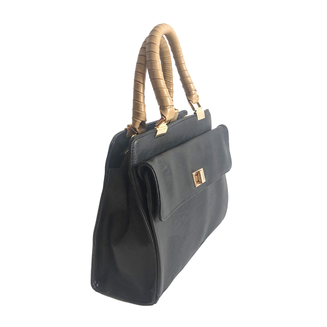 Bolso HNA de color negro, material piel vegana, broche en el centro para cerrar el bolso en material metálico y de color dorado, asa estática en la parte superior de color mostaza para ser tomado con la mano, detalles metálicos en color dorado.