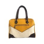 Bolso para dama HNA en la parte trasera de color mostaza, blanco y café, material piel vegana, viene con figura de triangulo y textura lisa, asa estática en la parte superior de color café, detalles metálicos en color dorado.