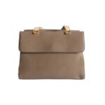 Bolso HNA de color café, material piel vegana, en la parte trasera es totalmente lisa, con una división con broche interno para abrir y cerrar, asa superior estática en color nude para tomar con una mano, detalles en metálico de color dorado.