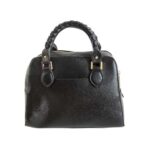 Bolso para dama HNA en la parte trasera de color negro, en material piel vegana, asa estática en la parte superior para ser tomada con la mano, detalles decorativos del bolso en metal y de color dorados.