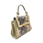 Bolso para dama HNA en color beige, material piel vegana, en la parte de enfrente, en el centro, tiene un estampado de animal print, cuenta con broche en la parte de enfrente de metal y color dorado para abrir y cerrar el bolso, asa estática en la parte superior del color del bolso para usar con la mano, detalles decorativos en metálico y color dorado.