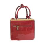Bolso para dama HNA de color rojo, material en charol, asa estática en la parte superior para tomar con la mano, cierre de metal en color dorado y rojo en la parte trasera del bolso.